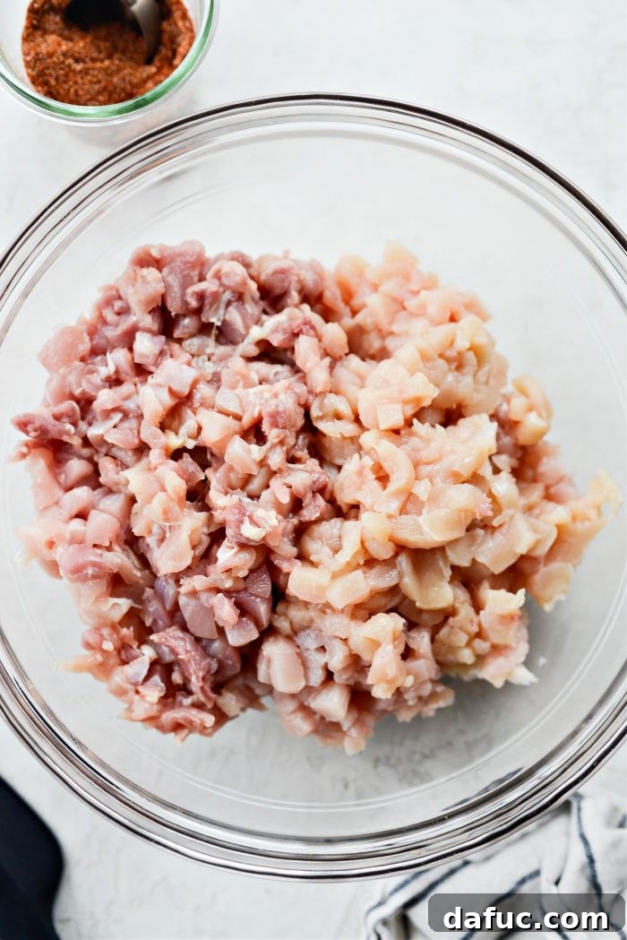 Finely minced boneless skinless chicken breast and thigh meat in a bowl, ready for seasoning