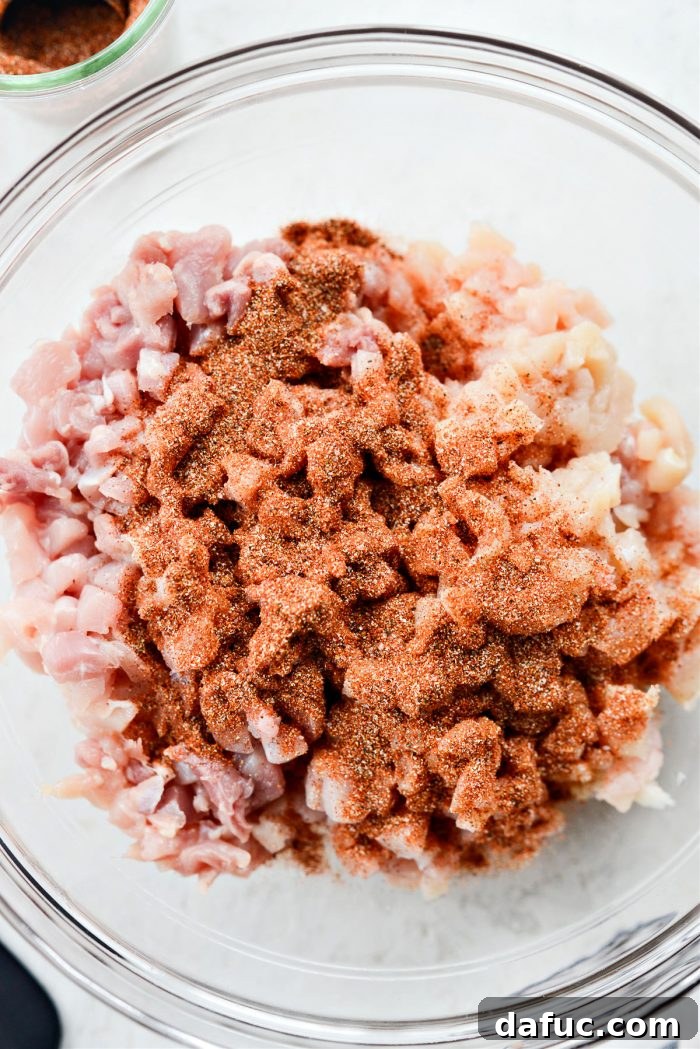 Adding homemade street taco seasoning to the minced chicken in a bowl