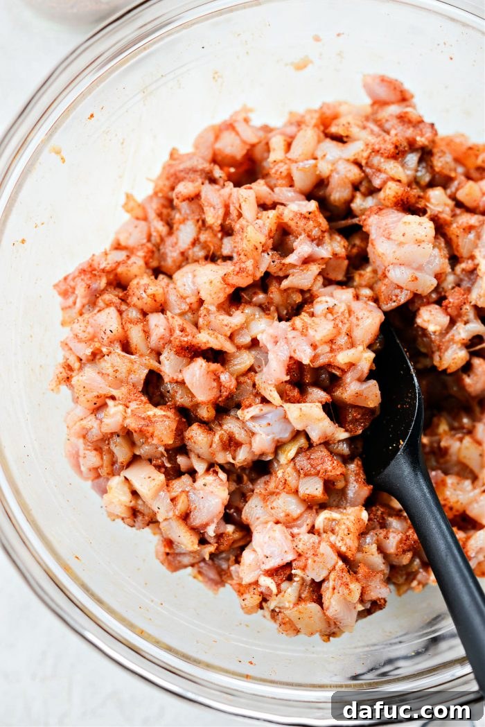 Tossing minced chicken with seasoning to ensure even coating