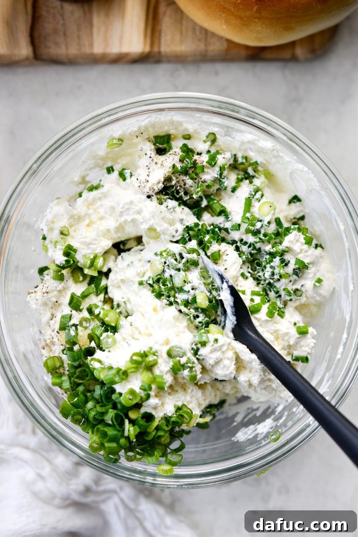 Sweet & Spicy Bagel with Zesty Chive Cream Cheese 6 A spatula mixing whipped cream cheese, chives, green onions, garlic, and black pepper