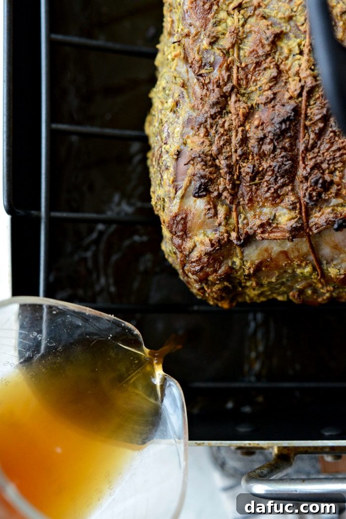 Rosemary Dijon Crusted Prime Rib with Pinot Noir Au Jus 20 Pouring beef broth into the roasting pan.