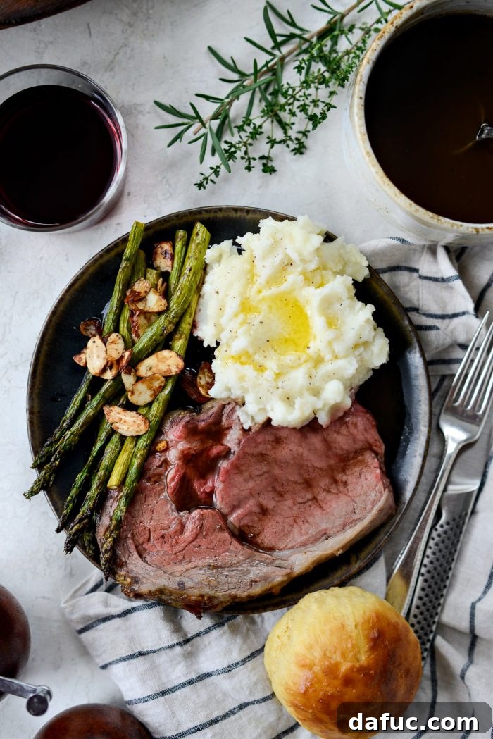 Rosemary Dijon Crusted Prime Rib with Pinot Noir Au Jus 27 Dijon Rosemary Prime Rib Roast on a black plate with sides.