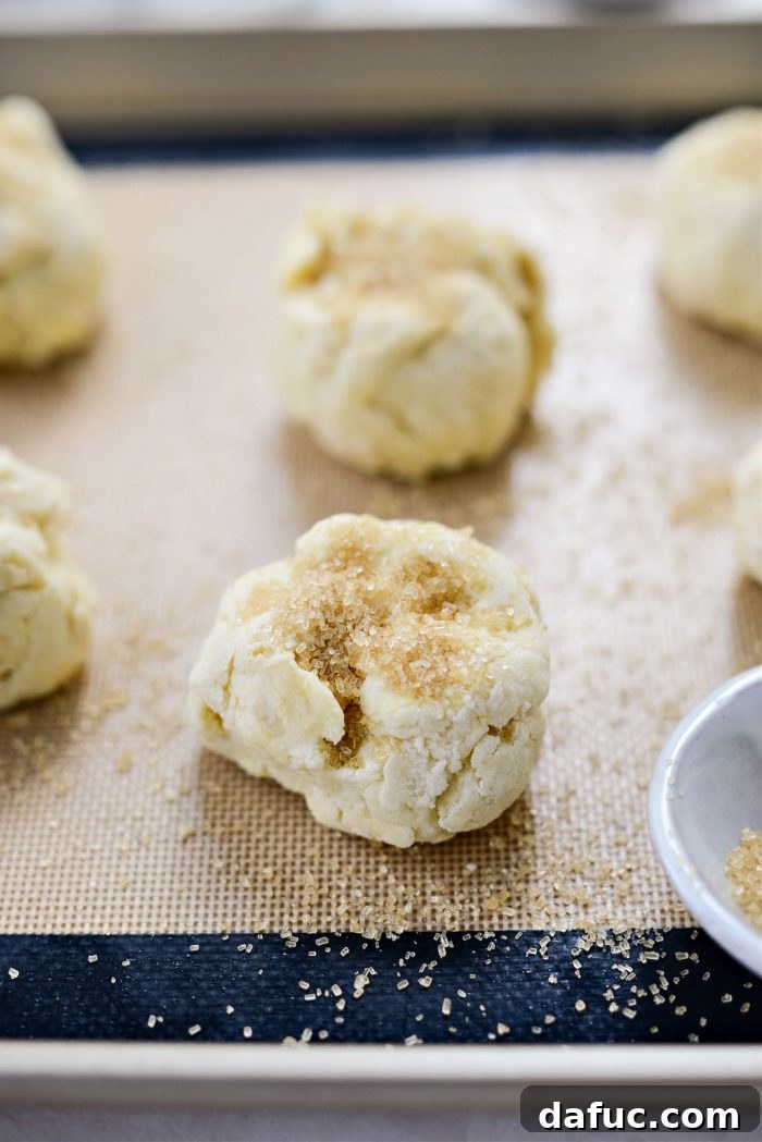 Shortcake biscuits placed on a lined baking sheet and sprinkled with turbinado sugar.