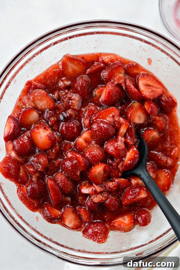 Mixed strawberries, jam, and sugar macerating in a bowl.