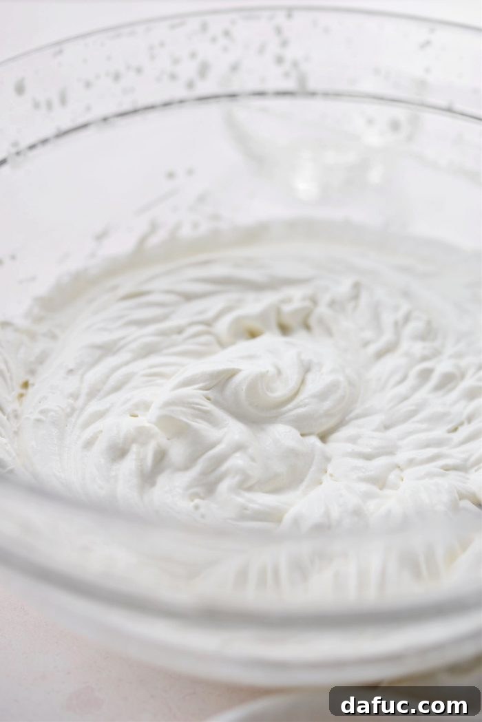 Homemade whipped cream in a mixing bowl with a whisk.
