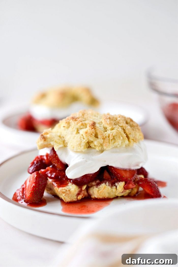 Layered shortcake with strawberries and whipped cream, topped with the biscuit half.