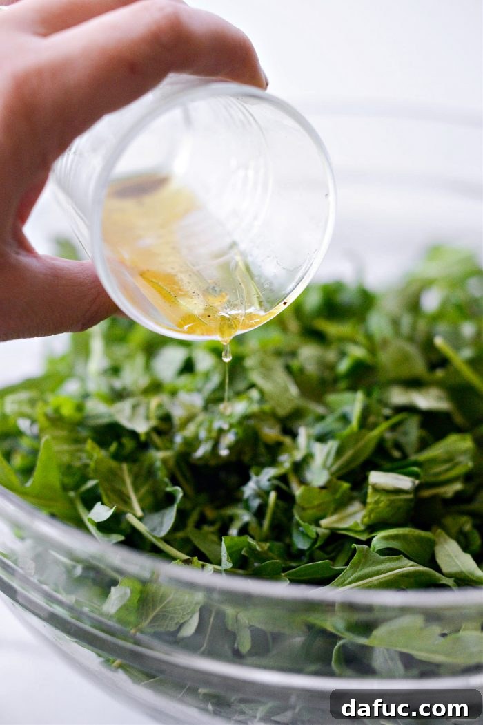 Summer Berry Caprese Salad 7 Champagne vinaigrette being poured over arugula and herbs