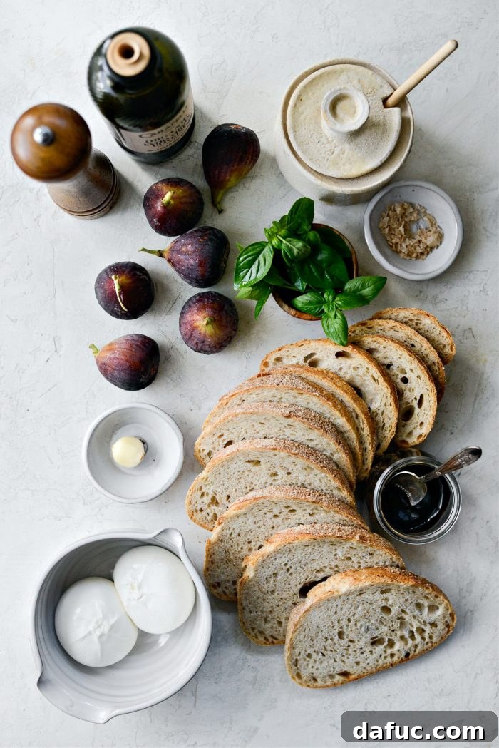 Ingredients for Honey Balsamic Fig and Burrata Crostini laid out on a wooden surface, including bread, figs, burrata, honey, and balsamic glaze.