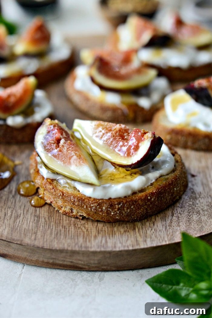 Assembled crostini topped with burrata, quartered figs, and a drizzle of honey