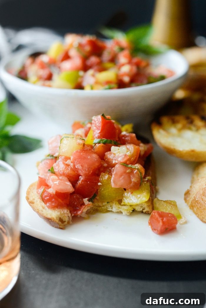 Vibrant Heirloom Tomato Bruschetta 20 A vibrant platter of Heirloom Tomato Bruschetta with a bowl of the topping and fresh basil leaves, ready for enjoyment.