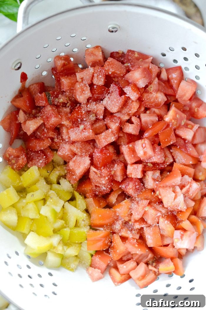 Vibrant Heirloom Tomato Bruschetta 6 Chopped heirloom tomatoes are gently tossed with a sprinkle of kosher salt in a white colander.