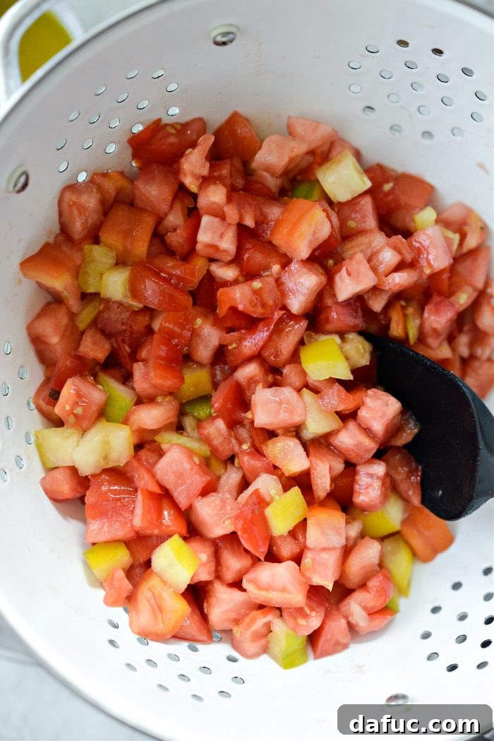 Vibrant Heirloom Tomato Bruschetta 7 A hand gently tossing chopped heirloom tomatoes in a colander, ensuring even distribution of salt.