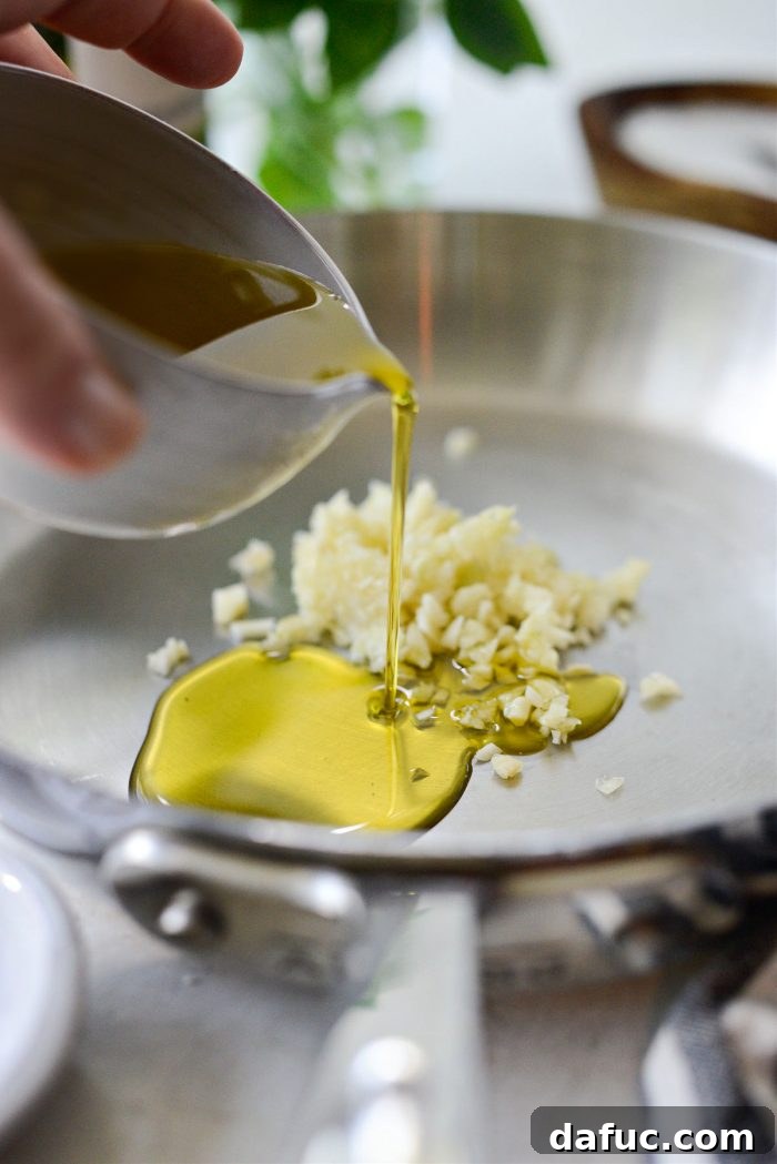 Vibrant Heirloom Tomato Bruschetta 10 Extra virgin olive oil being poured over minced garlic in a small skillet.
