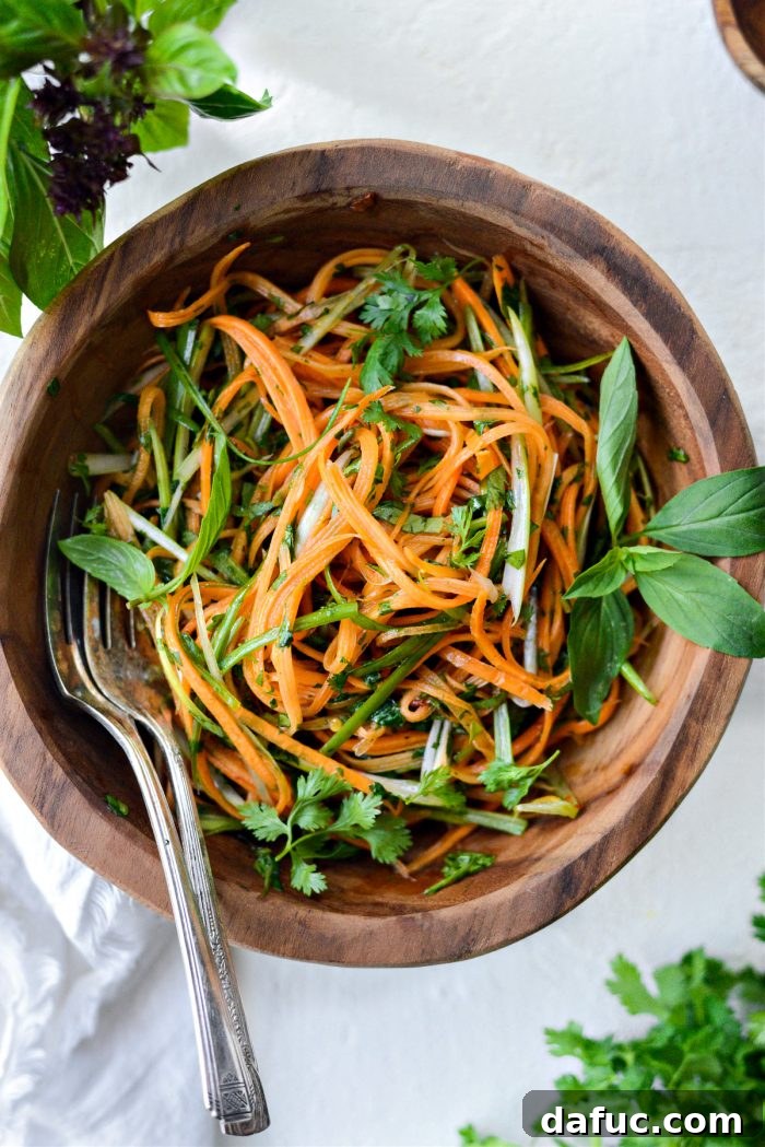 Vibrant Thai Carrot Slaw 2 Vibrant and fresh Thai Carrot Slaw in a white bowl, garnished with herbs.