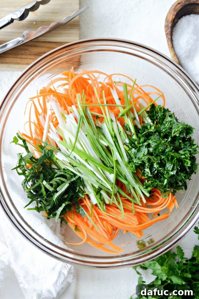 Vibrant Thai Carrot Slaw 7 Julienned carrots, green onions, Thai basil, and cilantro in a bowl, ready to be tossed with dressing.