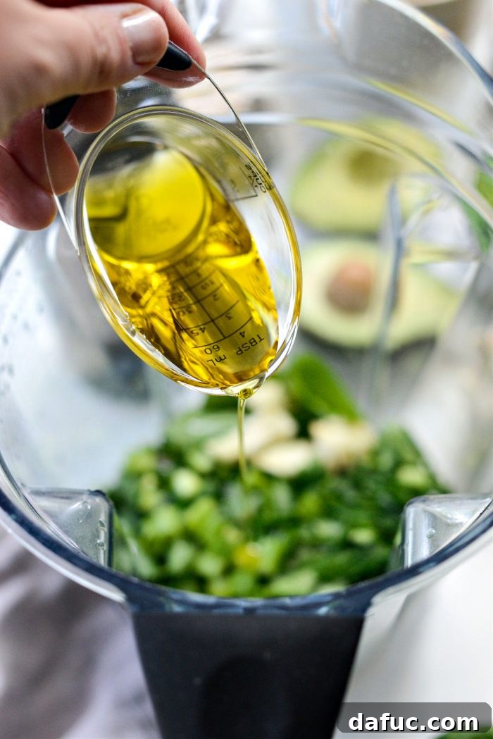Vibrant Green Goddess Hummus 7 Pouring extra virgin olive oil into the blender with other ingredients