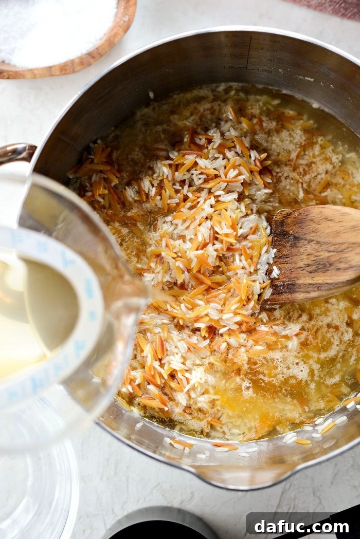 Stirring rice and toasted orzo together in a saucepan before adding liquid