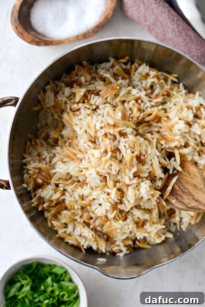 Lid being removed from a saucepan, revealing perfectly cooked, fluffy rice pilaf