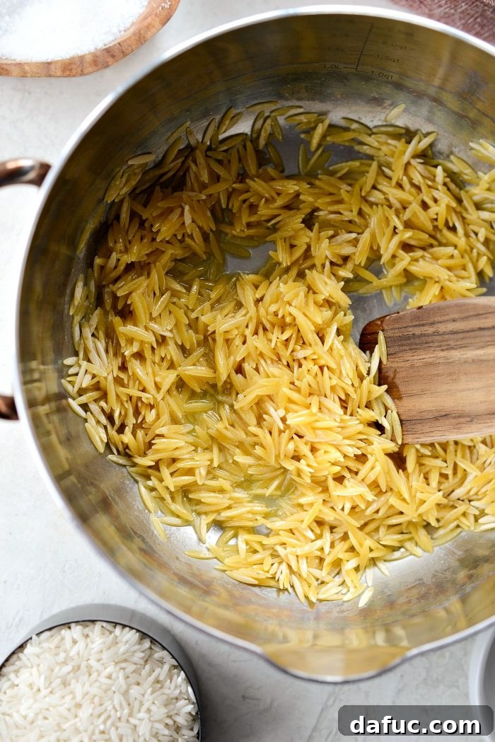 Adding orzo pasta to melted butter in a saucepan for toasting