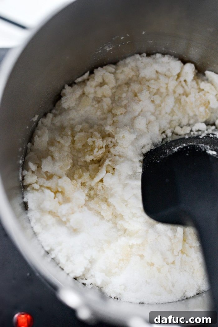 Continuing to stir as sugar begins to clump and melt