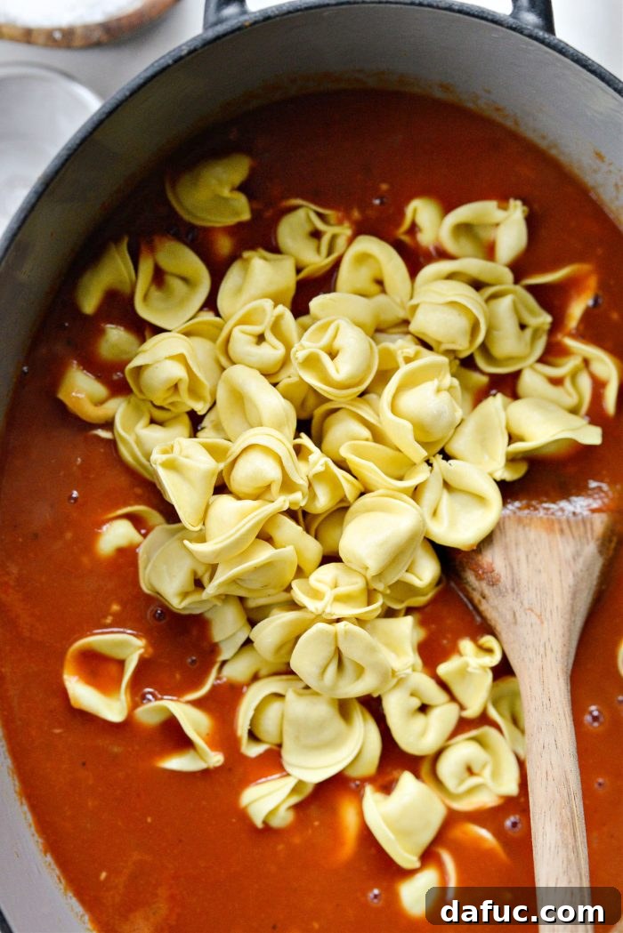 Adding cheese-filled tortellini to the simmering soup.