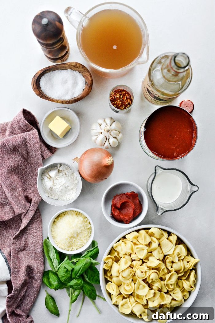 Fresh ingredients laid out for Tortellini Pasta alla Vodka Soup, including tomatoes, garlic, onion, and tortellini.