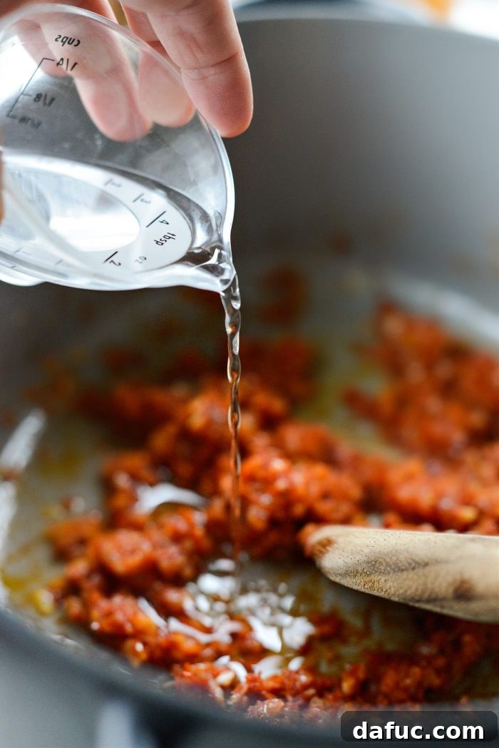 Adding vodka to the tomato mixture.