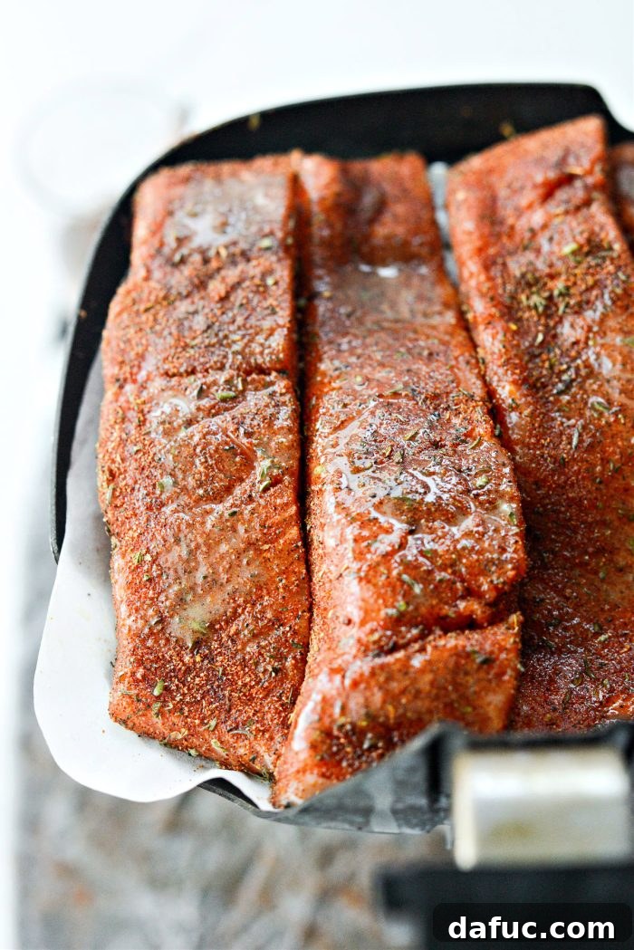 Arranging seasoned salmon fillets in the air fryer basket before cooking