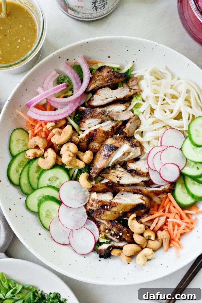 Savory Sesame Grilled Chicken Noodle Bowls 9 Arranging various ingredients like noodles, chicken, and vegetables in a large shallow bowl for a grilled sesame chicken noodle bowl