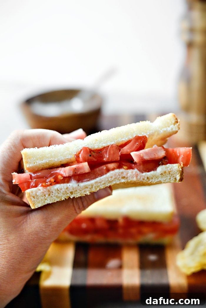 Close-up of a perfectly constructed Classic Tomato Sandwich, ready to be enjoyed, highlighting the layers.