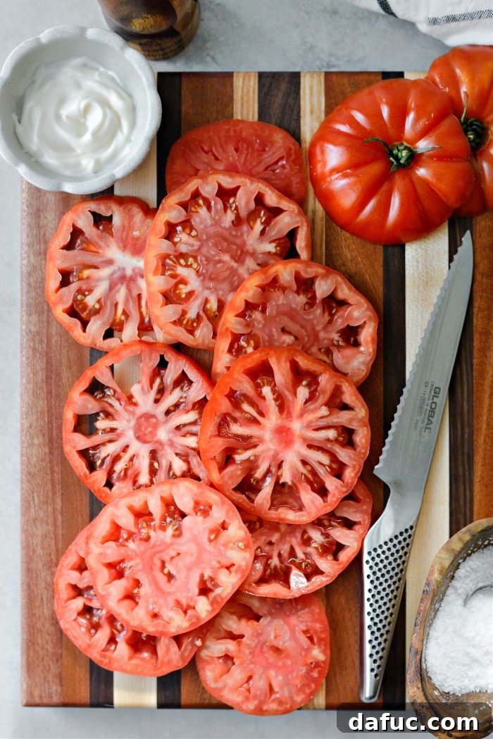 Perfectly sliced red tomatoes, ready for sandwich assembly, showcasing their vibrant color and juicy texture.