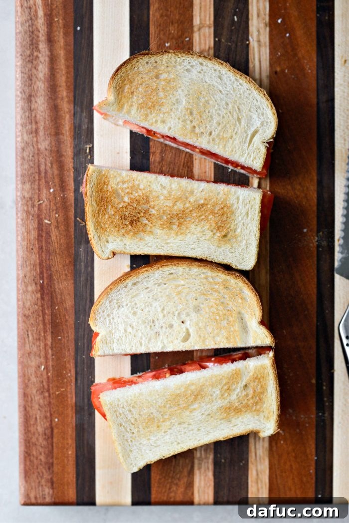 The final step in assembling a Classic Tomato Sandwich: topping with the second slice of bread and gently pressing before cutting.