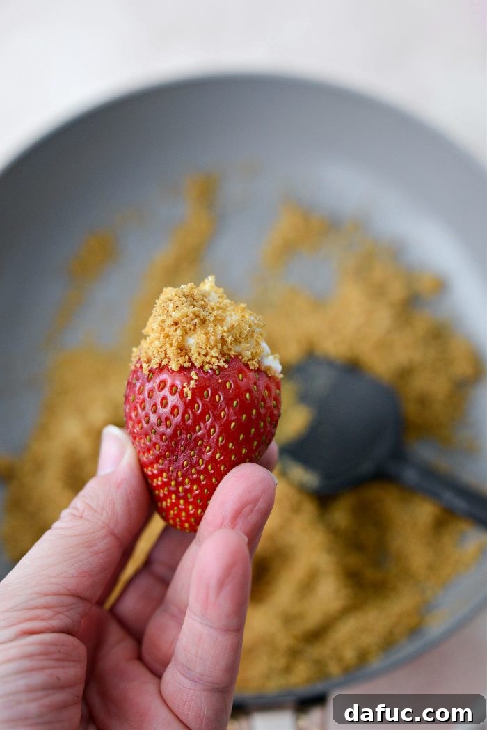 Creamy Strawberry Cheesecake Bites 12 Cheesecake filled strawberry being sprinkled with graham cracker crumbs