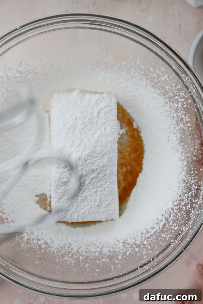 Creamy Strawberry Cheesecake Bites 8 Ingredients for cheesecake filling in a bowl: heavy cream, vanilla, cream cheese, and sifted powdered sugar