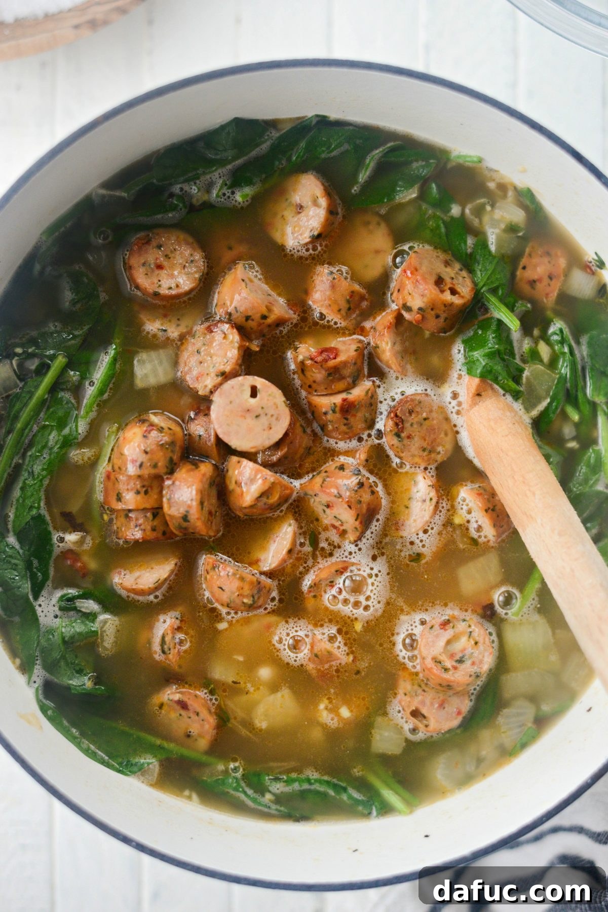 Rustic Chicken Sausage and White Bean Pot 16 Ladle dipping into the Chicken Sausage White Bean Stew in a pot