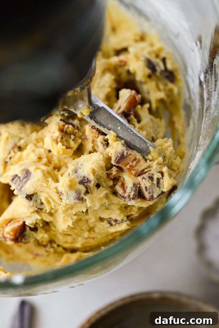 Mixing chopped Snickers into cookie dough until just combined