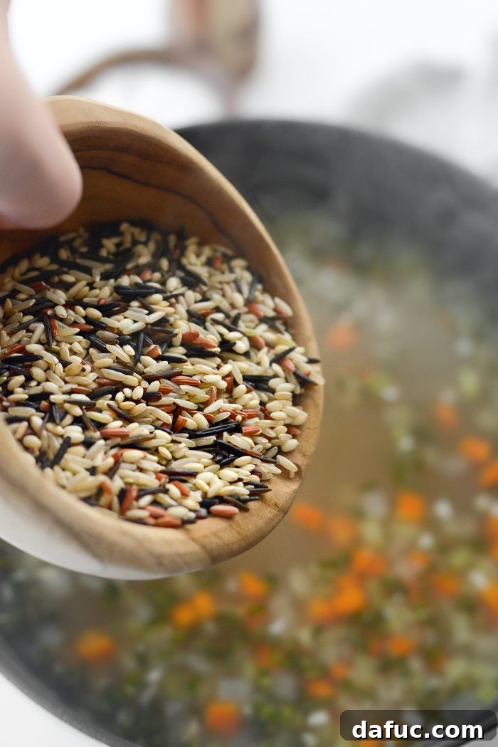 Adding wild rice blend to the boiling broth.