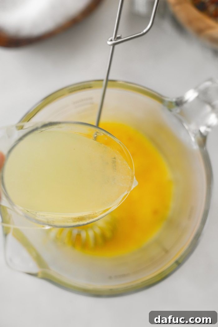 Whisking lemon juice into beaten eggs.