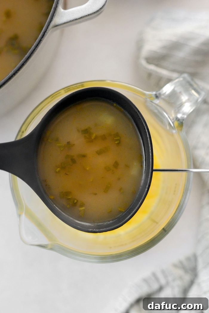 Slowly ladling hot broth into the egg and lemon mixture to temper.