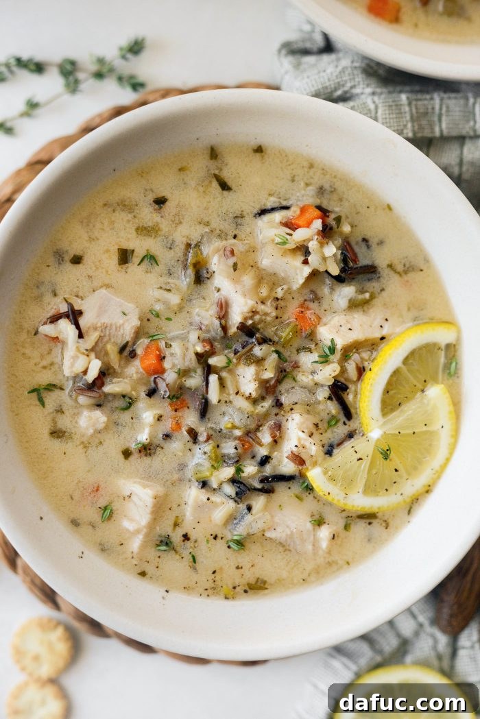 A bowl of Turkey Lemon Wild Rice Soup, garnished.