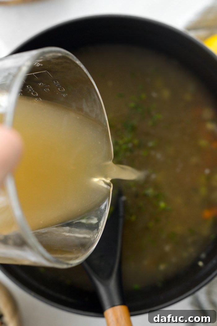 Pouring chicken broth into the Dutch oven.