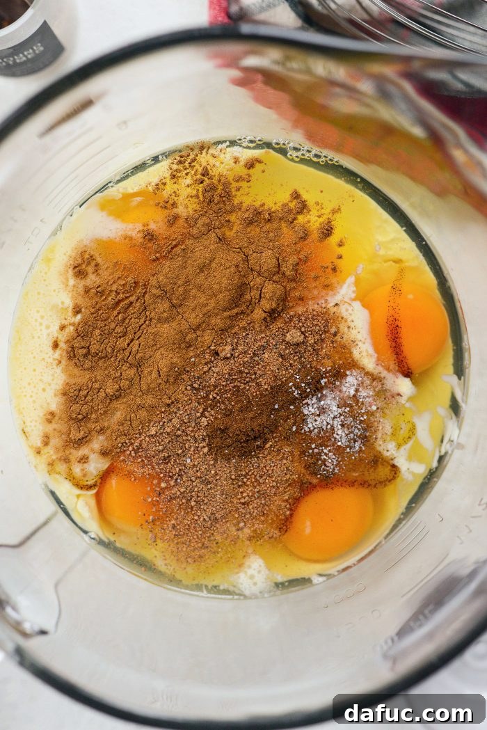 A bowl with eggs, eggnog, sugar, vanilla paste, and spices, ready to be whisked for the custard.