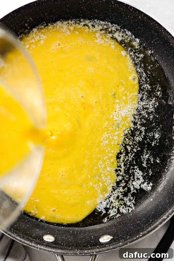 Pouring beaten eggs into a hot skillet