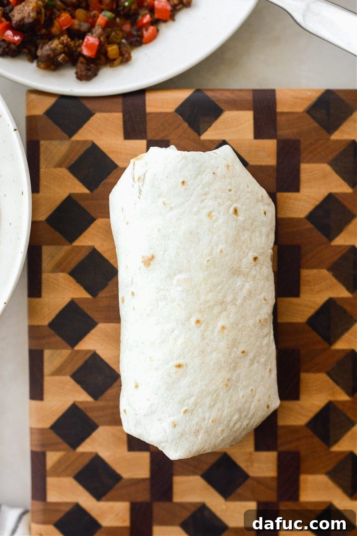 Folding in the sides and tightly rolling a breakfast burrito
