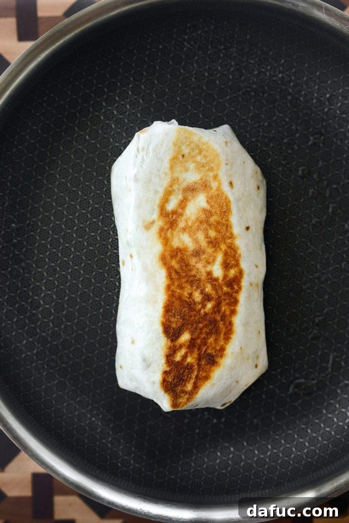 Pan-toasting a rolled breakfast burrito in a skillet