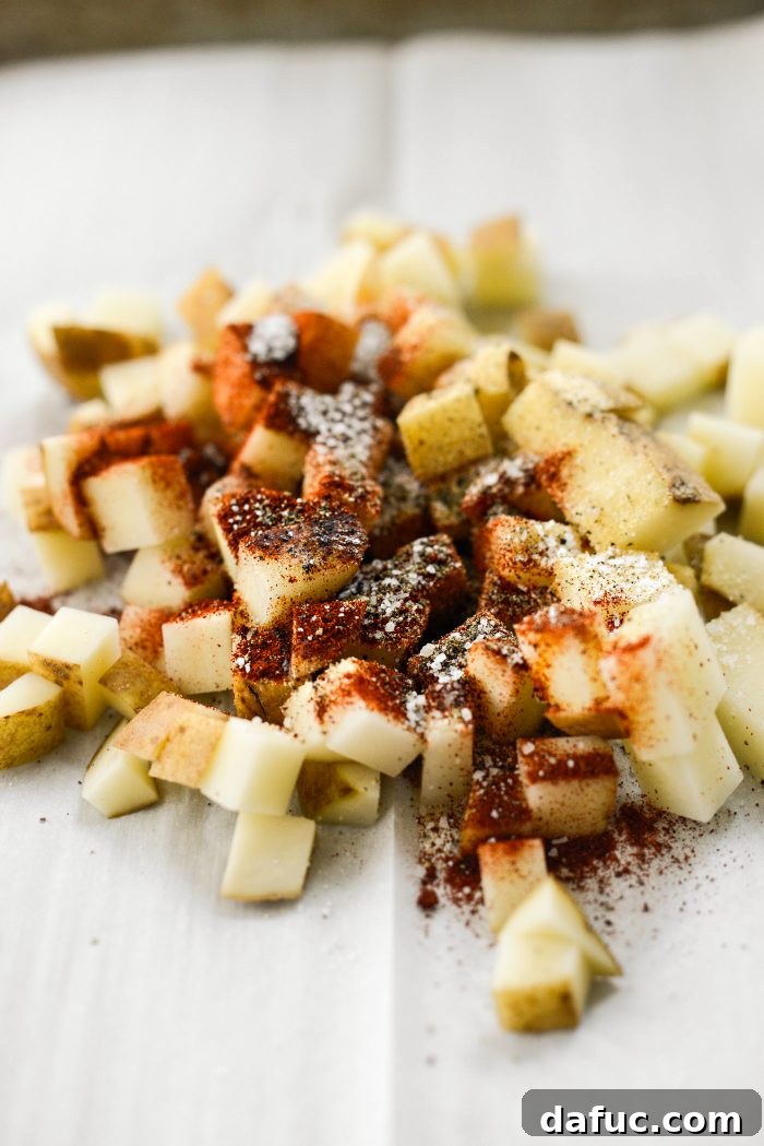 Diced russet potatoes tossed with oil and spices on a baking sheet