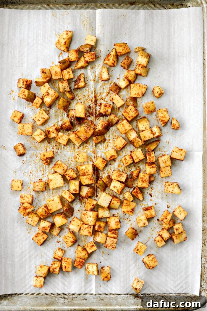 Spreading seasoned potatoes in an even layer on a baking sheet