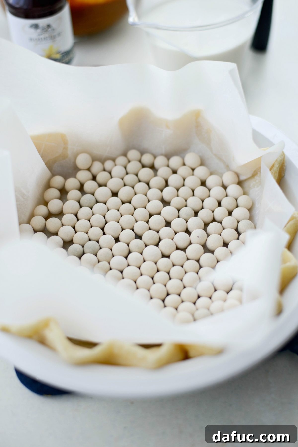 Pie crust lined with parchment paper and filled with pie weights for blind baking