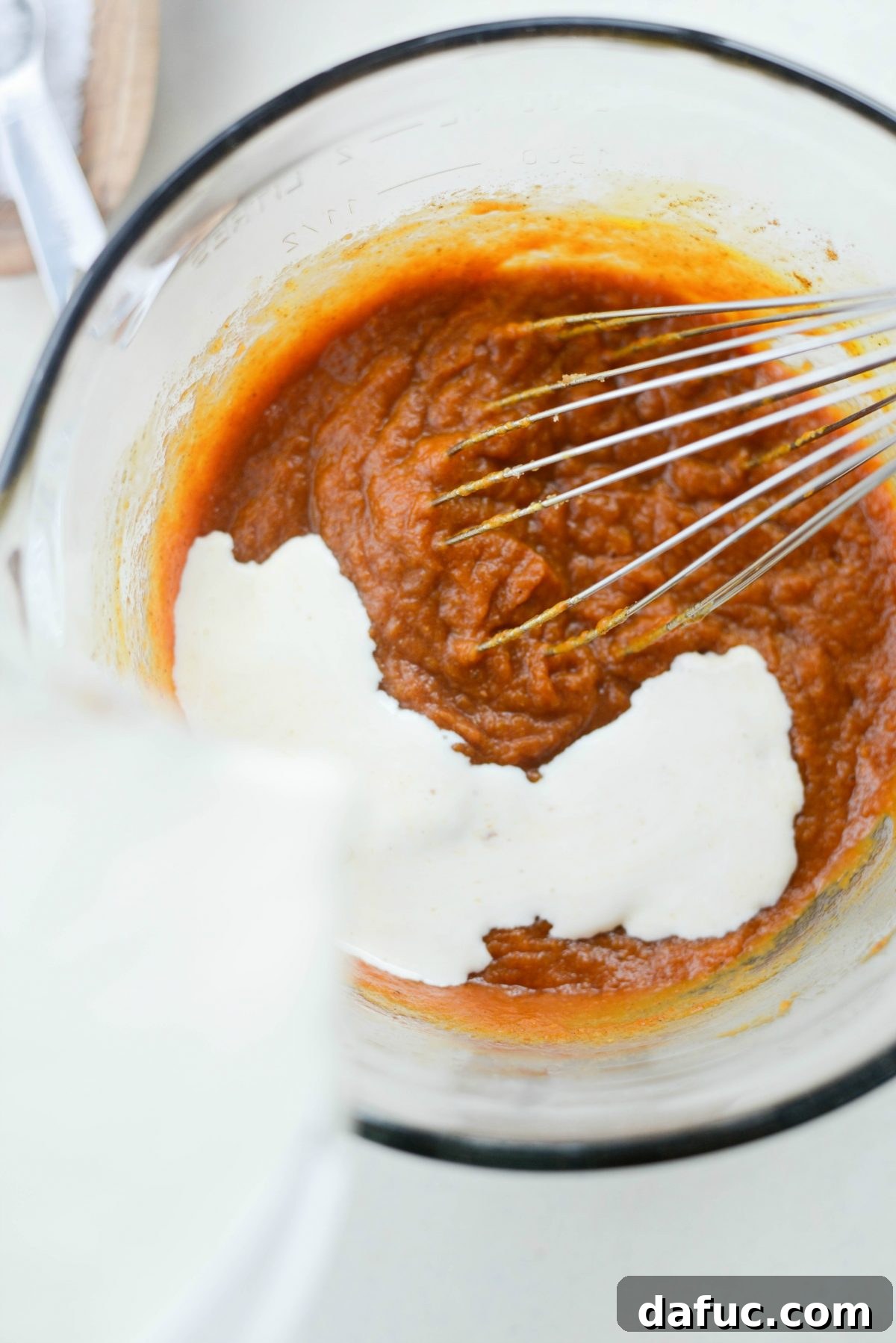 Pouring heavy cream into the pumpkin pie filling mixture