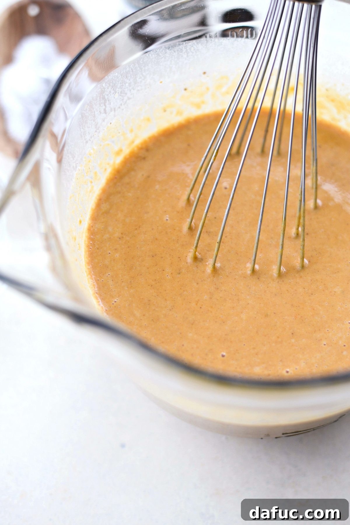 Whisking milk and cream into the pumpkin pie filling until fully blended